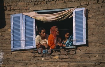EGYPT, Nile Valley, Luxor, City housing with women at open window with blue and white wooden