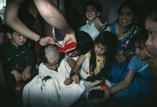RELIGION, Hindu, Hindu family participating in head shaving of young son.