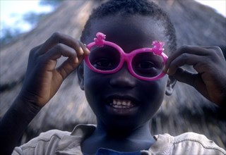 ETHIOPIA, Children, Portrait of a young Dimma Sudanese boy with pink sunglasses
