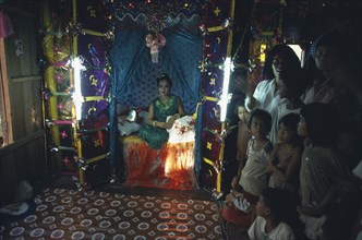 CAMBODIA, , Moslem child bride sitting in decorated cove with family outside