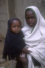 NIGERIA, Kano, Young girl holding baby.