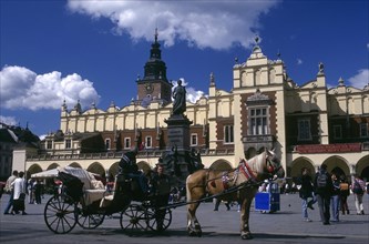 POLAND, Krakow, Horse drawn cart standing in the Market Square or Rynek Glowny with the facade of