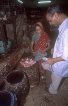 BANGLADESH, Dhaka, Women selling freshly slaughtered chicken pieces to a male buyer.