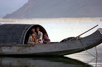 VIETNAM, Central, Lang Co, Father with three children on their house boat on the Lagoon