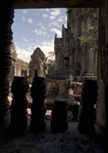 CAMBODIA, Angkor, View through archway over pink sandstone ruins of Banteay Srei or The Citadel of