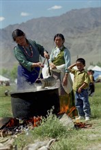 INDIA, Ladakh, Woman heating milk in large pot at the 14th Dalai Lamas birthday celebrations