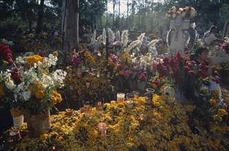 MEXICO, Michoacan State, Patzcuaro, Graves in Tzurumutaro cemetery decorated with candles marigold