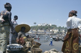 GHANA, Elmina, Dockside fish vendors and the Fort behind