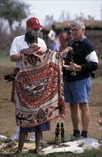 KENYA, , An American tourist haggles with a Maasai woman in a cultural manyatta set up to interface