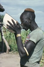 SUDAN, Tribal Peoples, Dinka man drinking groundnut gruel at ceremony welcoming young men back to