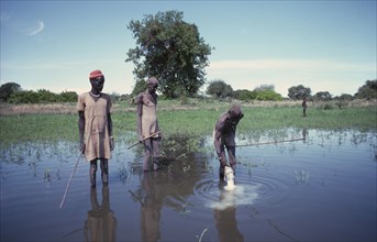 SUDAN, Tribal Peoples, Dinka men making votive offering of milk in sacred pond.