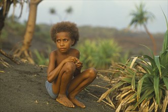 PACIFIC ISLANDS, Melanesia, Vanuatu, Tanna Island.  Ni Vanuatu child sitting on volcanic sand.