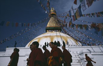 20049356 NEPAL  Kathmandu Tibetan families and monks of the Gelug pa sect walking around the Bodhanath stupa during New year festivities.  Lines of prayer flags overhead.
