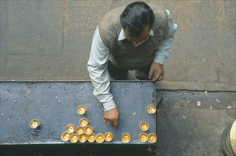 NEPAL, Patan, Looking down on man lighting butterwick candles at the Hiranyavarna Mahavihara Golden
