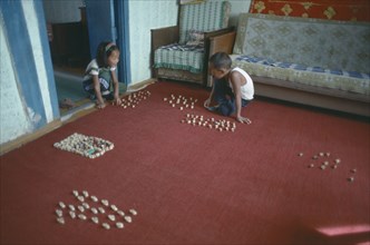 MONGOLIA, Children, Playing, Domestic interior with children playing game using knuckle bones to