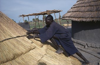 SUDAN, Tribal People, Dinka man thatching hut in cattle camp.