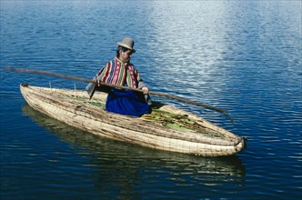 PERU, Puno, Lake Titicaca, Uros woman on reed boat rowing to floating island.