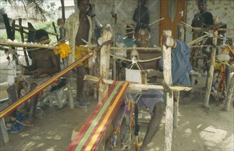 GHANA, Ashanti Region, Kumasi, Weaver at hand loom prodcungin traditional multi coloured Kente