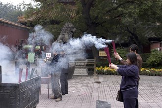 CHINA, Beijing, Lama Temple. People lighting incense during worship in the Temple courtyard