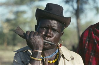 UGANDA, Karamoja  , Portrait of a Dodoth Karamojong warrior blowing an antelope horn to call a