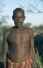 UGANDA, Karamoja, Tribal Poeple, Portrait of Karamojong Mathenico clan warrior.  Scarification