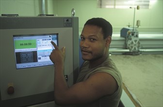 SOUTH AFRICA, Western Cape, Cape Town, Worker setting up automatic fabric cutting machine at Pre