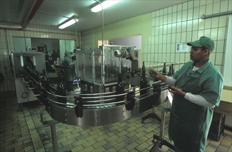 SOUTH AFRICA, Western Cape, Paarl, Worker putting top seals on wine bottles at Fairview wine estate