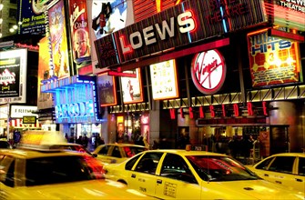 USA, New York State, New York City, Times Square illuminated at night with passing yellow taxi cabs