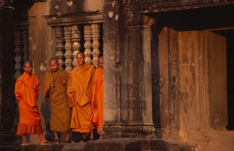 CAMBODIA, Siem Reap, Angkor Wat, Monks standing outside the west gallery at sunset