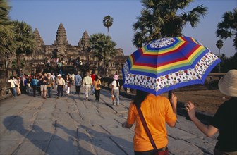 CAMBODIA, Siem Reap Province, Angkor Wat, Tourists on stone causeway leading to temple complex.