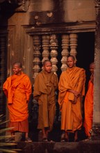 CAMBODIA, Siem Reap Province, Angkor Wat, Buddhist monks standing in front of window of upper level
