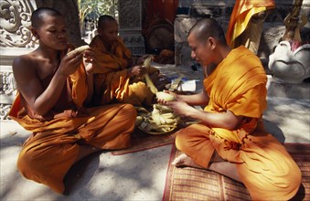 CAMBODIA, Siem Reap Province, Angkor Thom, Buddhist monks eating steamed and boiled corn donated by