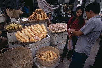 CAMBODIA, Siem Reap, Market stall selling bread with vendor and customer