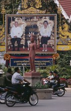 CAMBODIA, Siem Reap, Poster of Sihanouk and his wife by the side of a roundabout with motorbikes