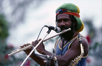 PAPUA NEW GUINEA, Port Moresby, Rastafarian musician singing and playing flute at a concert.