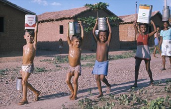 BRAZIL, Teresina, Group of young children of mixed race carrying water in various metal containers