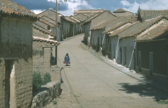 BOLIVIA, Chuquisaca, Tarabuco, Town in the Altiplano or Bolivian Plateau.  Woman carrying two