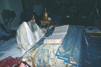ENGLAND, Religion, Sikhism, Sikh Holy man reads the Guru Granth Sahib Holy Book.
