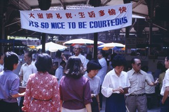 SINGAPORE, General, Street scene with mixed crowd below government banner stating Its So Nice To Be