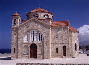 CYPRUS, Cape Drepanon, Agios Georgiou, Exterior of church with red tiled roof and bell tower.