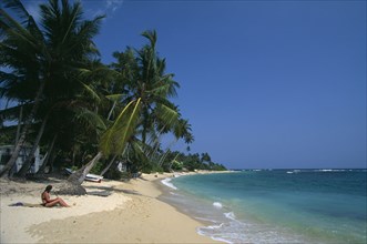 SRI LANKA, Unawatuna, Tourists on narrow strip of sandy beach fringed with palms at popular south