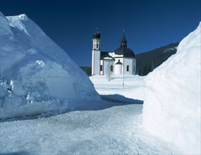 AUSTRIA, Tyrol, Seefeld Village, View through snowy mounds toward the Seekirchl church on the edge