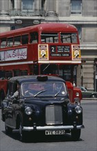 ENGLAND, London, Black cab and red bus driving around Marble Arch