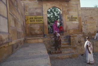 INDIA, Rajasthan, Jaisalmer, Women and children at Jain temple passing sign indicating bath room.
