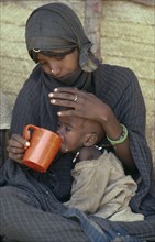 SUDAN, General, Mother feeding child at Sinkat feeding centre for malnourished children run by the