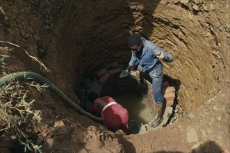 UGANDA, Aid, Trainee woman brick layer lining newly dug well near Jinja for project funded by Comic