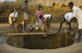 INDIA, Andhra Pradesh, Family collecting water from village well.