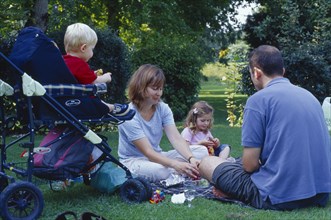 ENGLAND, West Sussex, Chichester, The Bishops Palace Gardens.  Young family having picnic.  Parents
