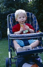 ENGLAND, West Sussex, Chichester, The Bishops Palace Gardens.  Boy aged one and a half drinking
