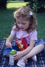 ENGLAND, West Sussex, Chichester, The Bishops Palace Gardens.  Girl aged three putting straw into